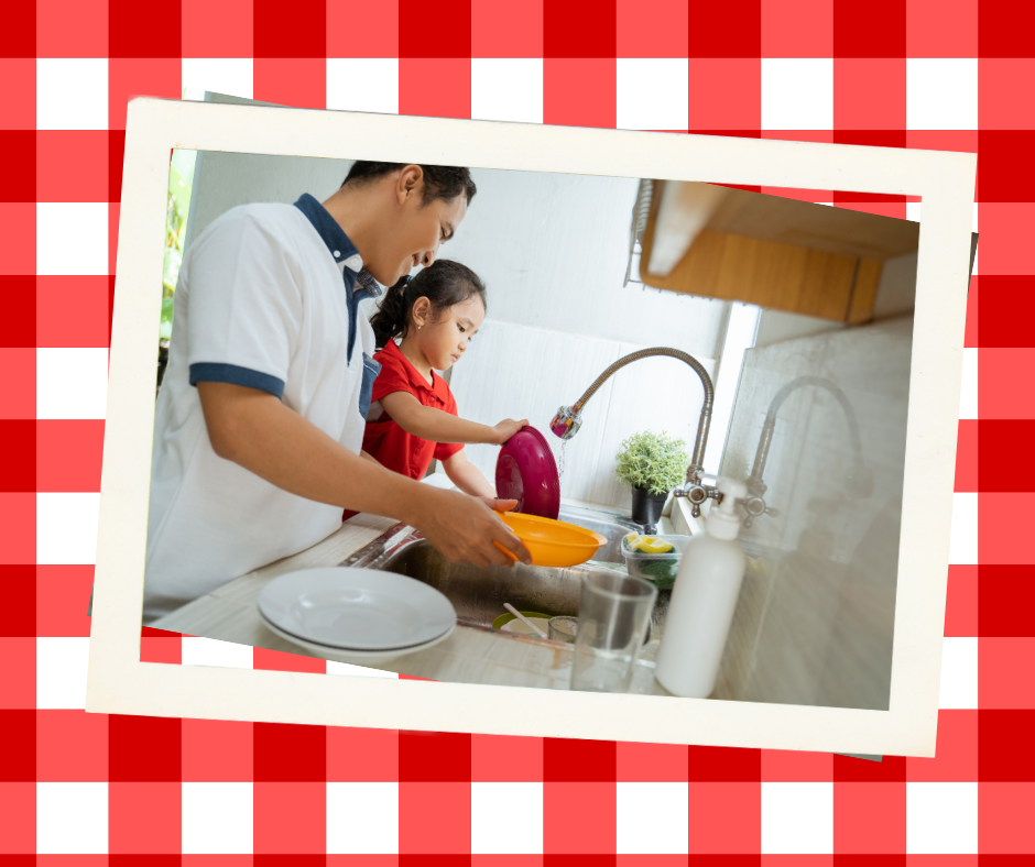 Adult man and young girl standing in front of kitchen sink. Man is holding yellow bowl. Girl is washing a dark pink bowl in the sink. A pile of white dishes is next to the sink.